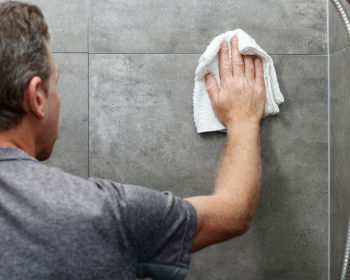 Homme nettoyant sa douche italienne avec un chiffon microfibre